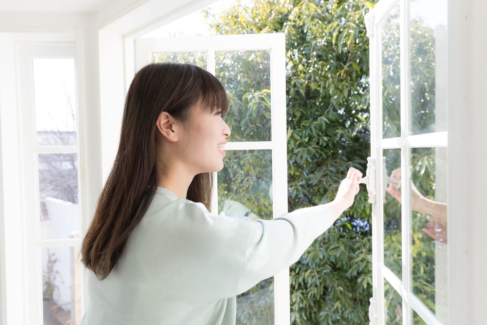 窓を開けて換気している女性