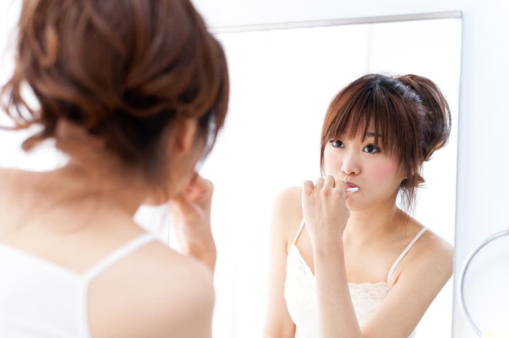 鏡を見ながら歯磨きをする女性